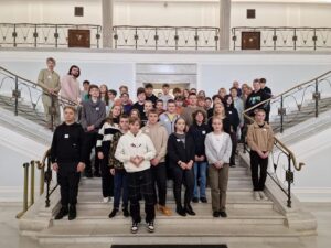 Zdjęcie przedstawia pozującą do fotografii grupę uczniów na schodach gmachu głównego Sejmu RP