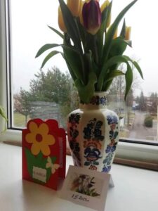 Wazon z tulipanami i stojące przed nim kartki z życzeniami.